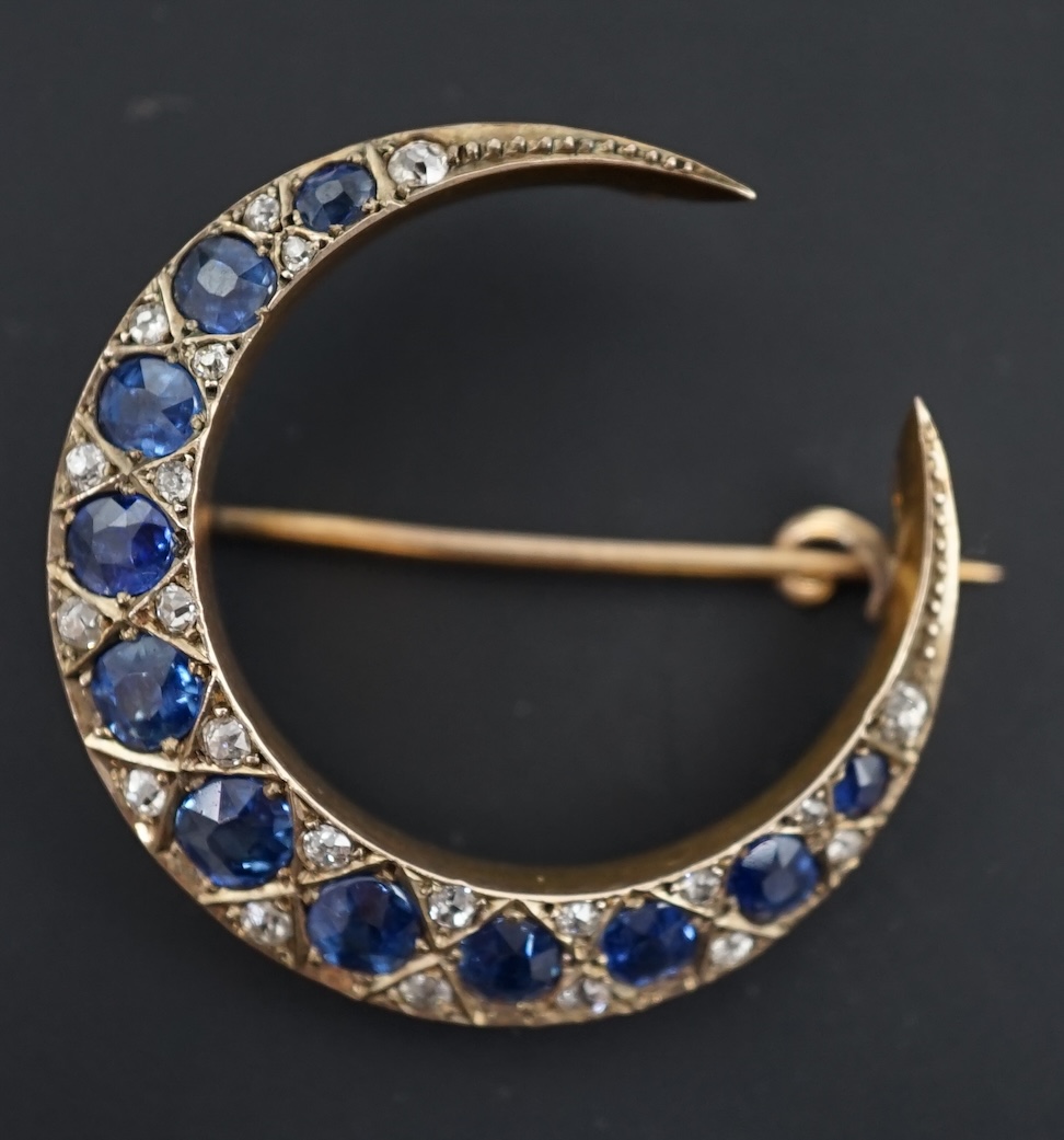 An early 20th century gold, graduated sapphire and diamond cluster set crescent brooch